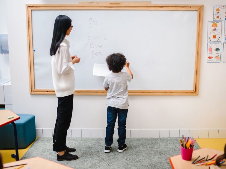 Teacher and child writing on a classroom whiteboard